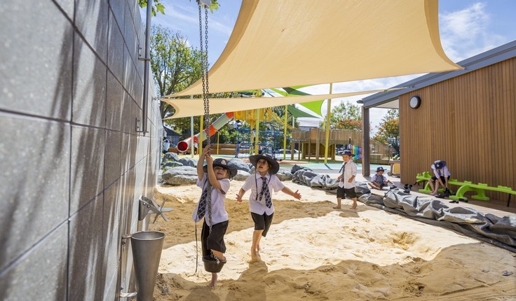 Shade sails which shelter the sandpit are supported by the concrete wall.