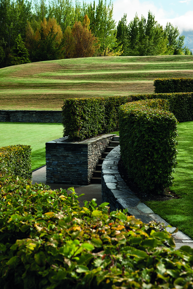 Curved steps and ramps amongst hedges lead to the tennis court.