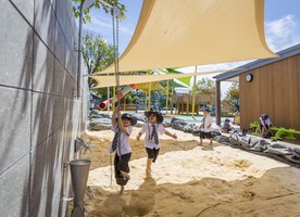Shade sails which shelter the sandpit are supported by the concrete wall.